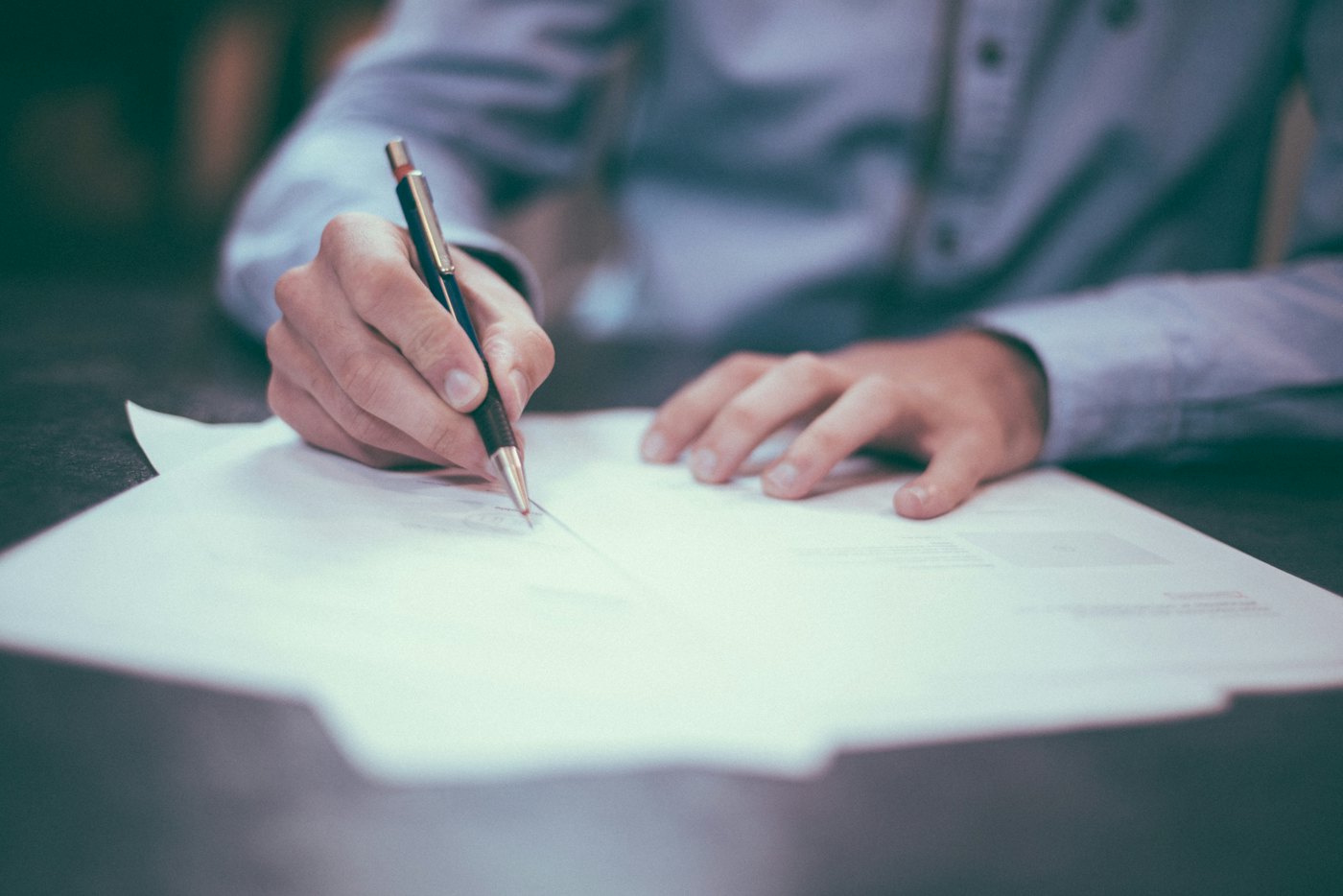 Hands signing paper documents at a desk